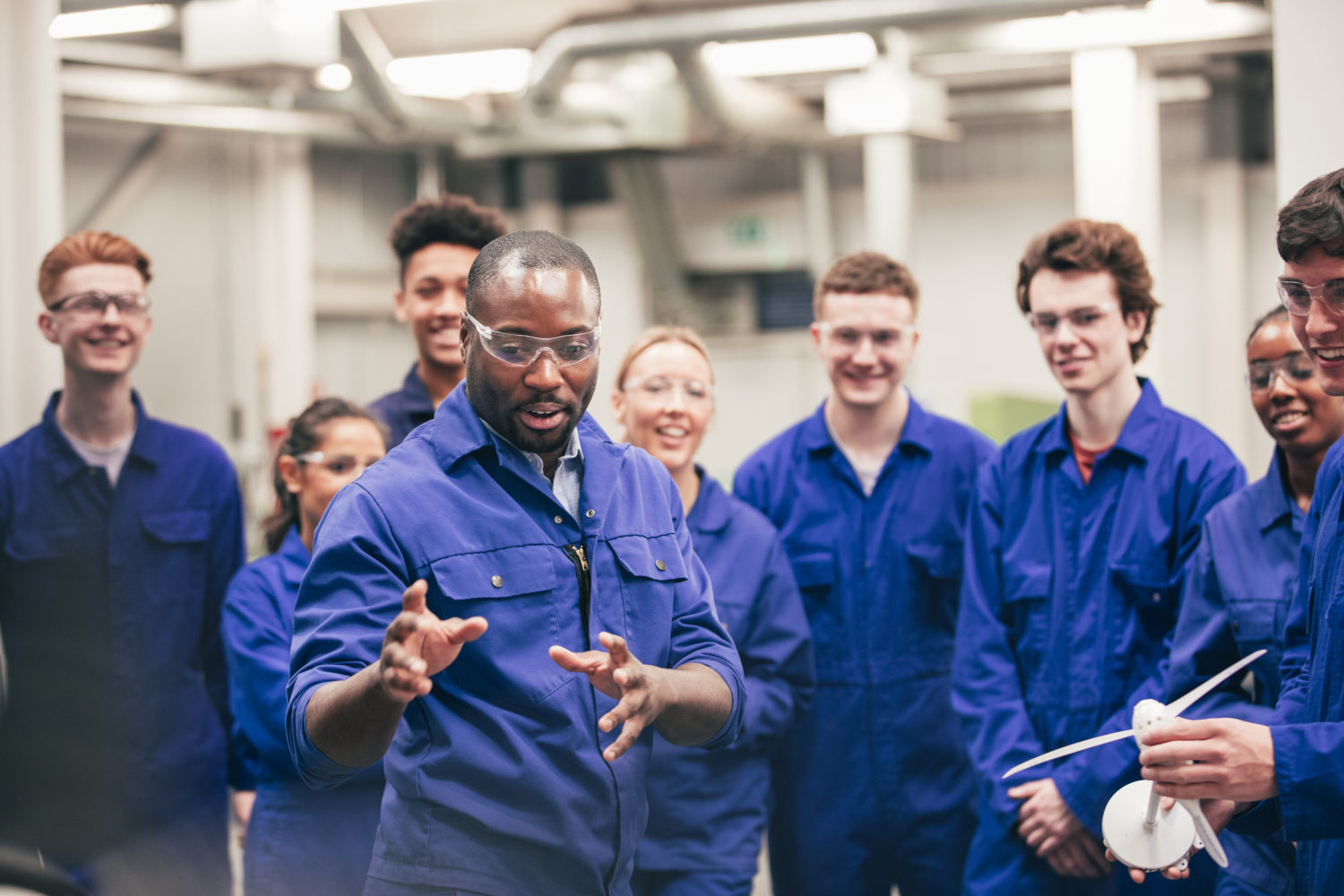 A tutor teaches his class about renewable energy in an engineering workshop.