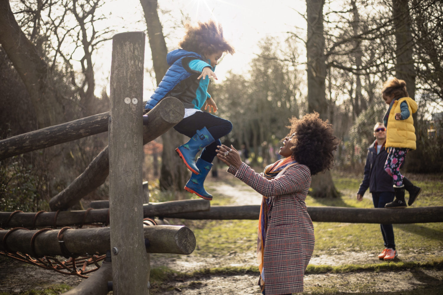 UK: A young boy jumping into his mother's arms off a wooden play area.