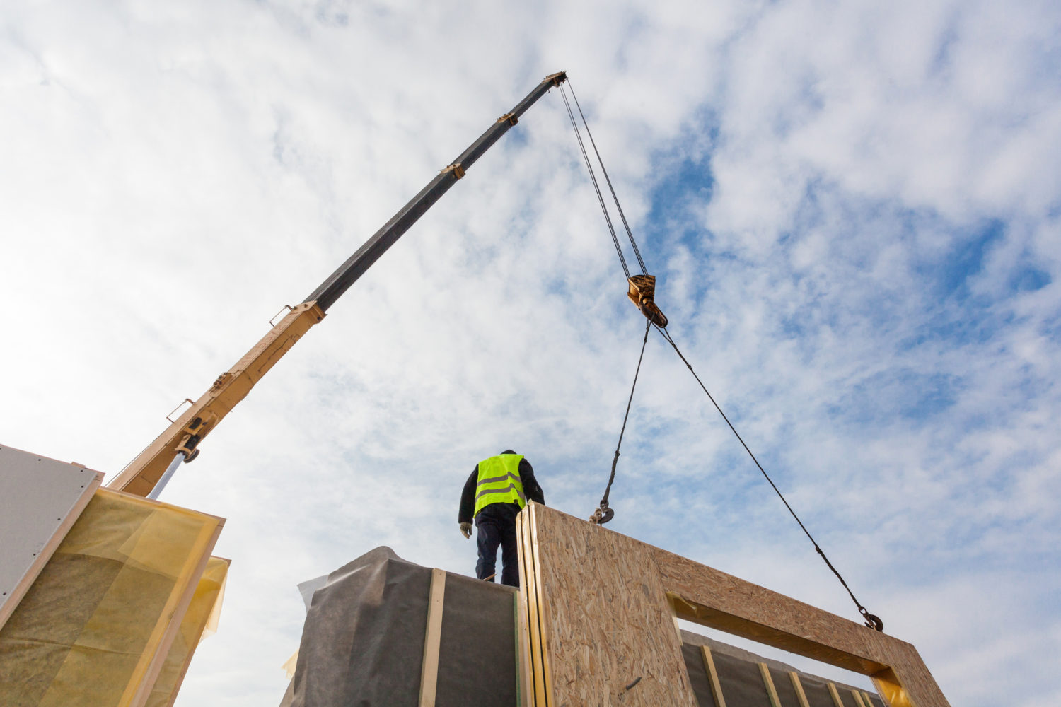 Roofer builder worker with crane installing structural Insulated Panels