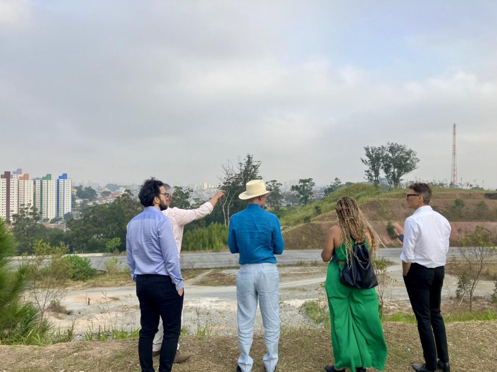 Mark Watts is accompanied by Gregor Robertson, and a delegation from C40 Cities and the City of São Paulo. They look out onto the green space currently under expansion.
